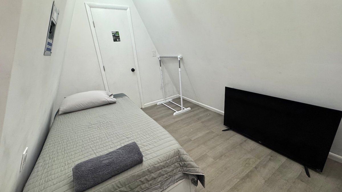 Loft bed beside the TV and clothing rack