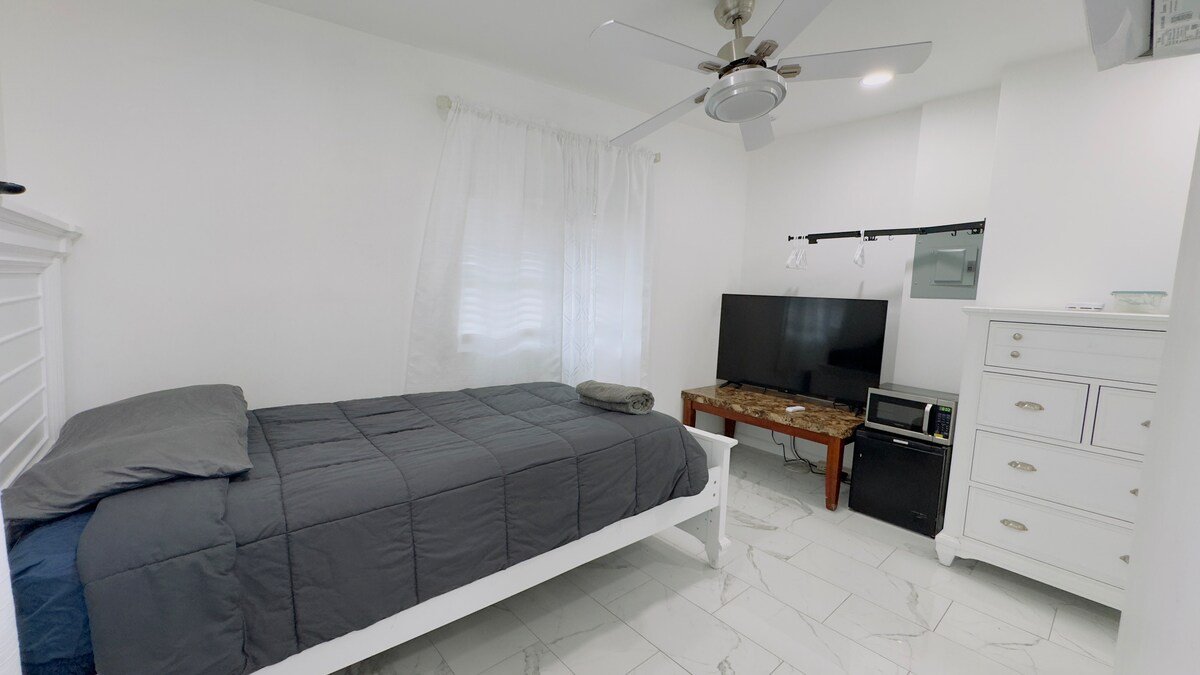 Private Studio Room with a bed, dresser, TV and white marble-look floors