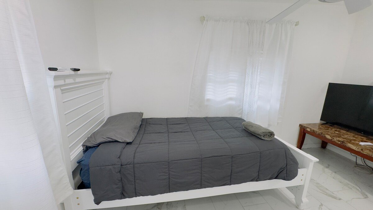 Studio bed with gray bedding beside the window