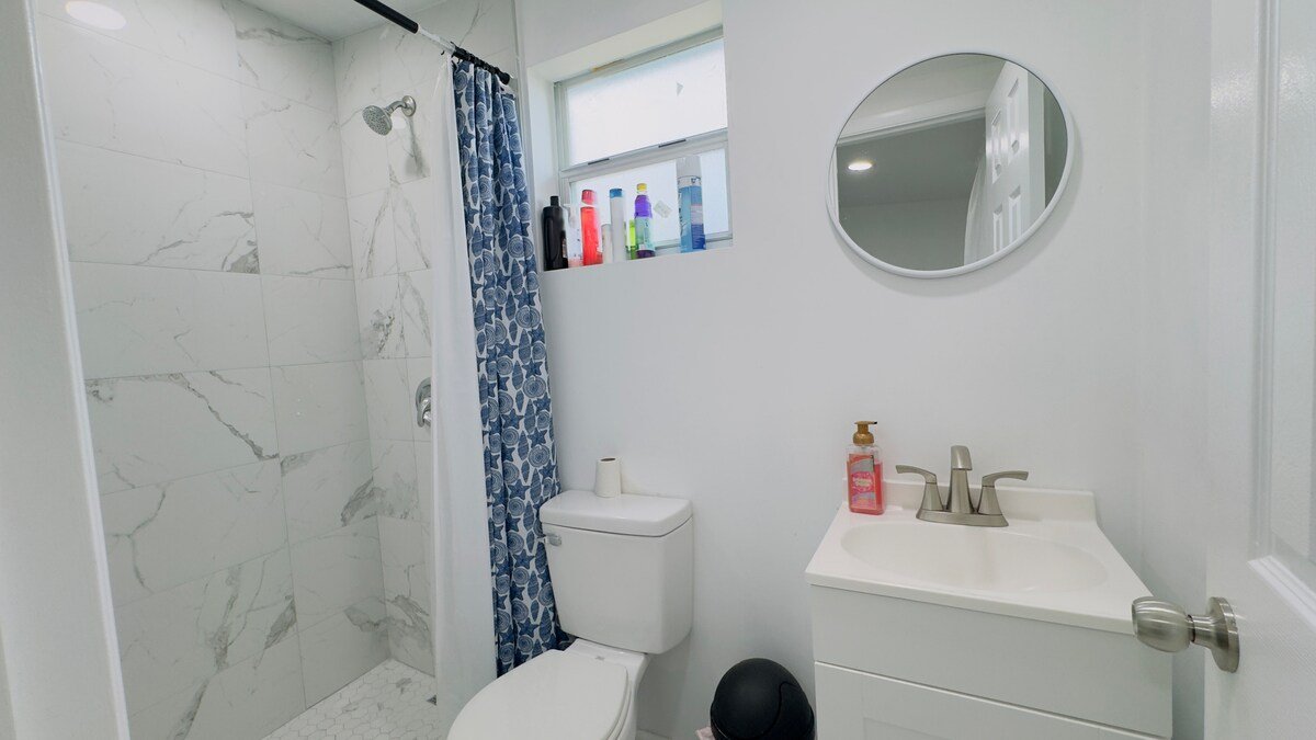 Dedicated bathroom with marble-look shower, vanity and round mirror