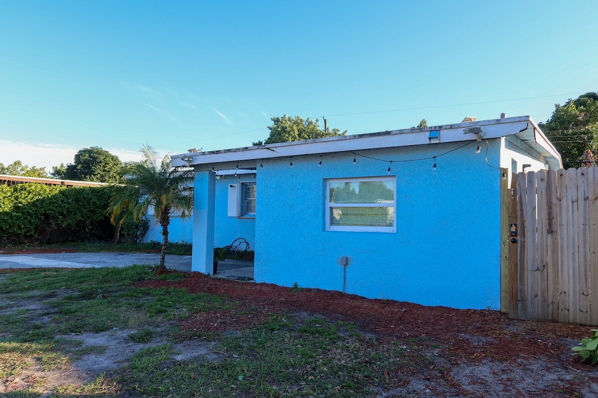 Exterior of the home with blue stucco walls and palm tree