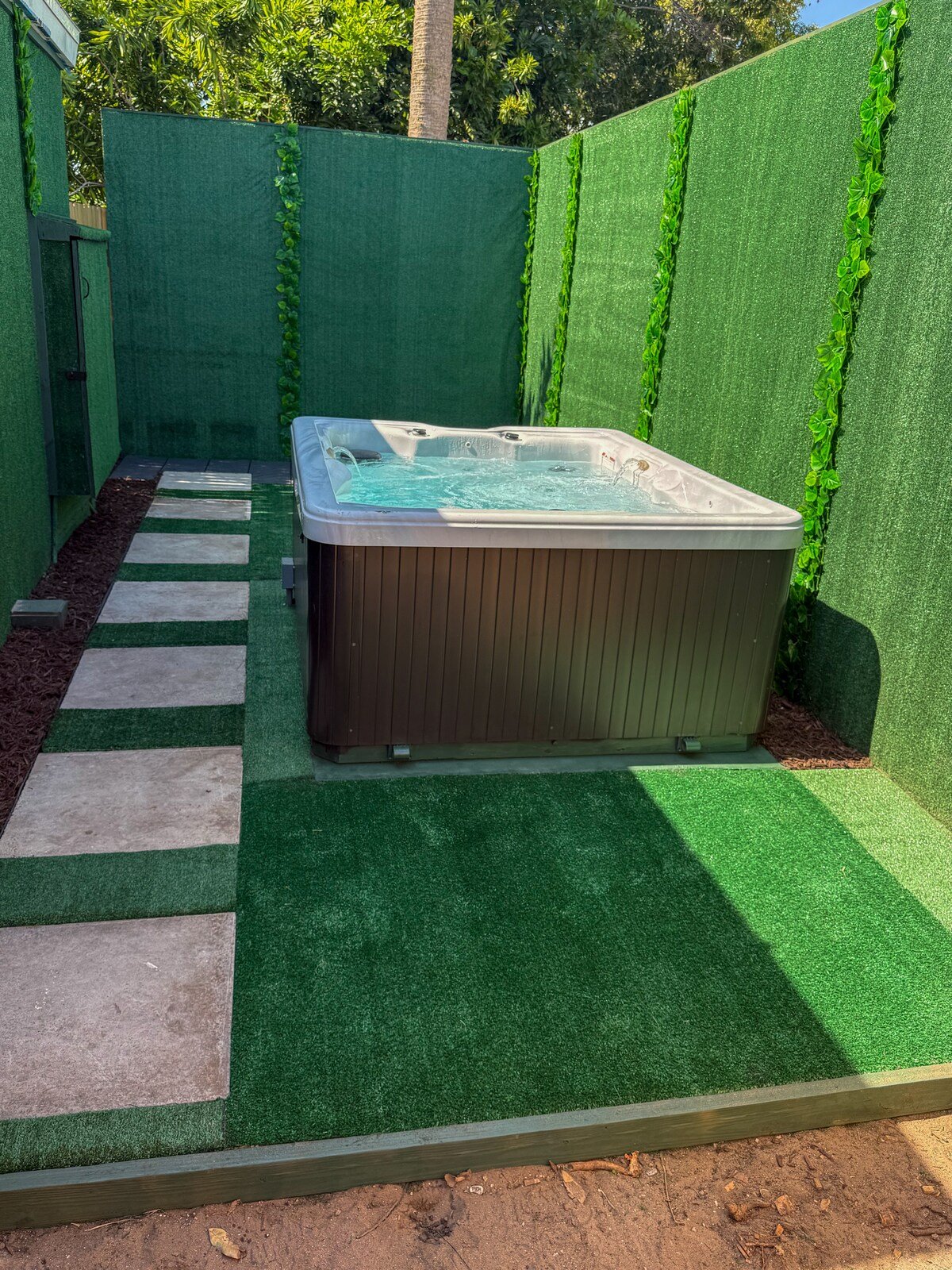 Hot tub with stepping-stone path and green privacy walls