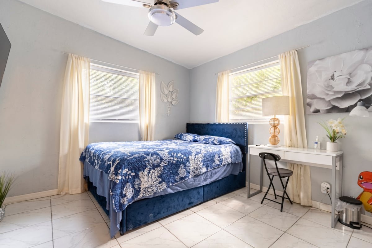 Room Beach bedroom with a queen bed, blue coverlet, desk and two windows