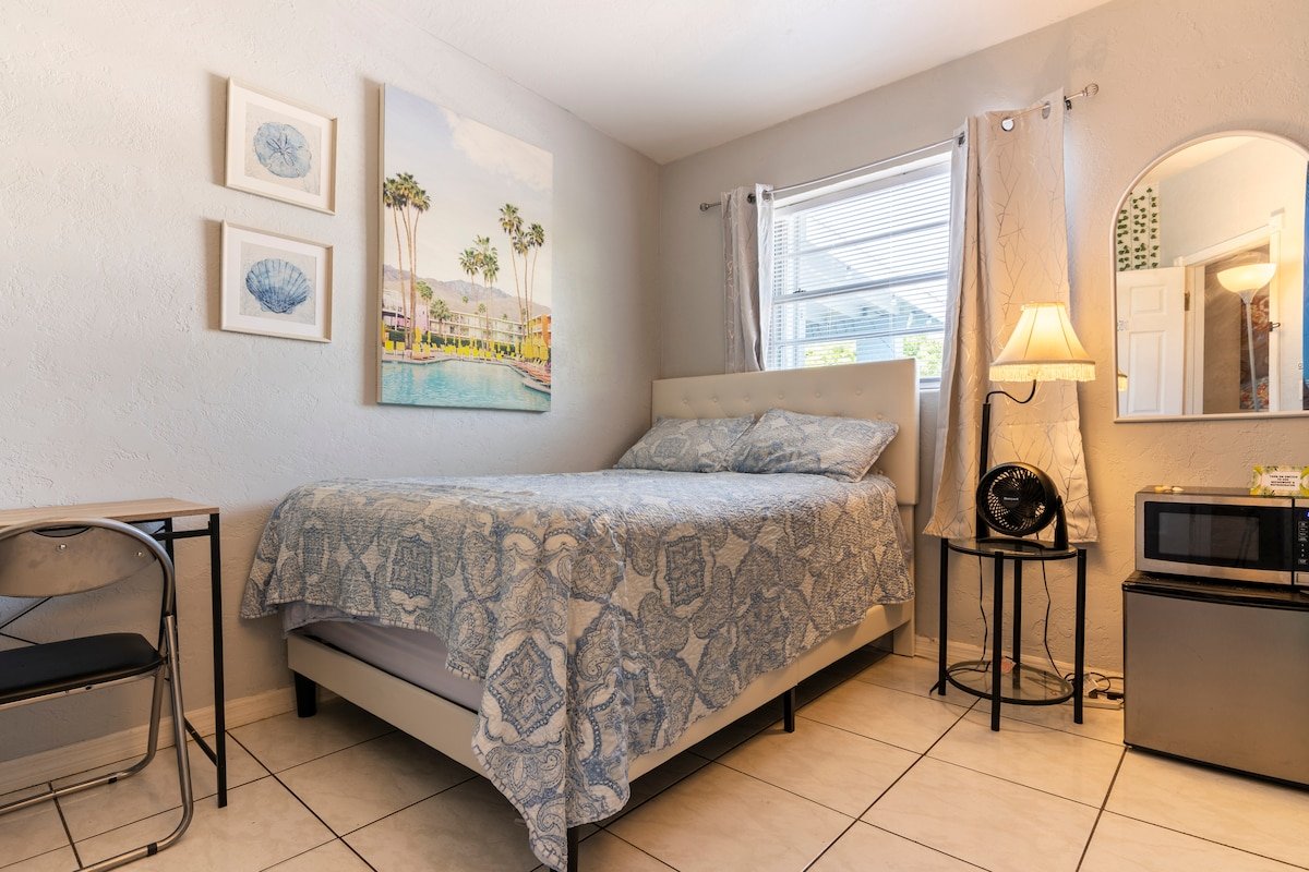 Room West with a queen bed, nightstand lamp and mini fridge